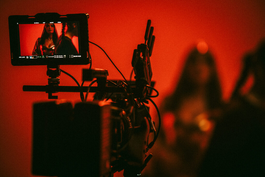Cinematic behind the scenes video shoot with on camera monitor showing talent under dramatic red lighting