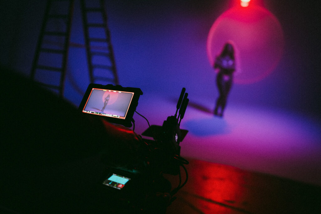 Studio video production with subject framed against colored backdrop and cinematic lighting