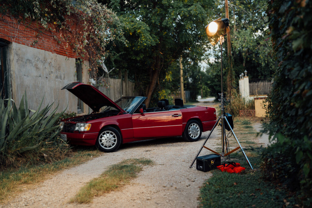 Lighting setup illuminating red convertible during cinematic video production shoot