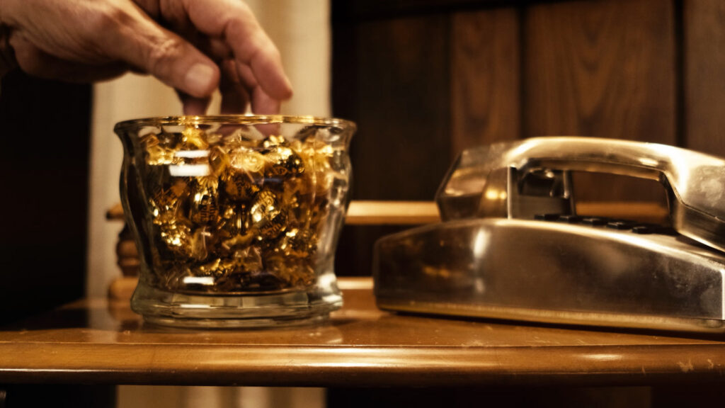 Cinematic close up of hand reaching into glass candy dish during film production