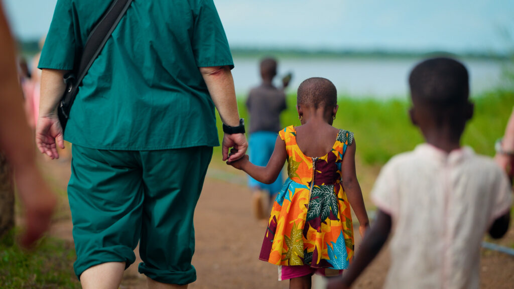 Cinematic video thumbnail of volunteer walking with child along rural path