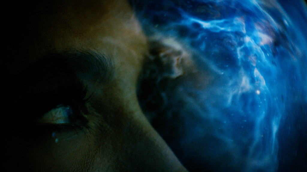 Close-up of eye reflecting blue cosmic visual effects