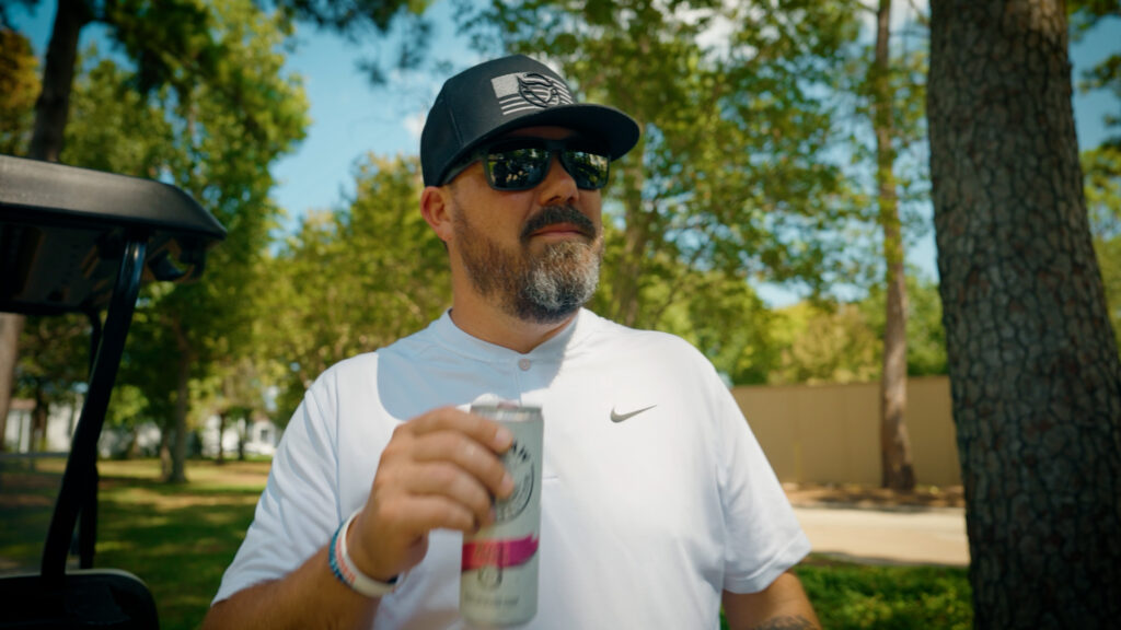 Man wearing sunglasses outdoors holding beverage during lifestyle commercial shoot