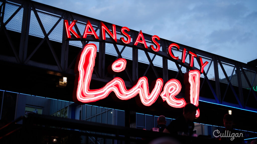 Kansas City Live neon sign glowing at night with people below