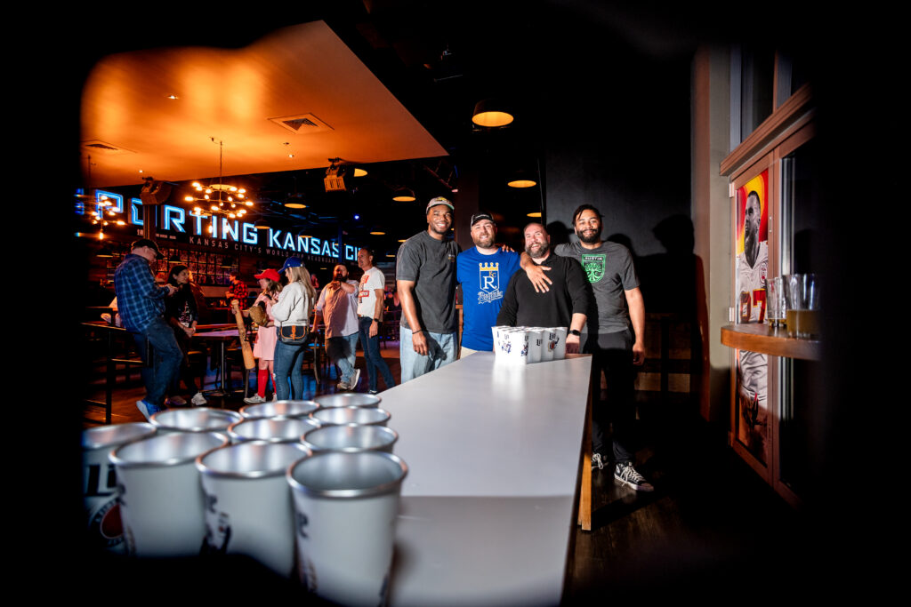 Group of men playing beer pong at Kansas City bar event with neon lighting