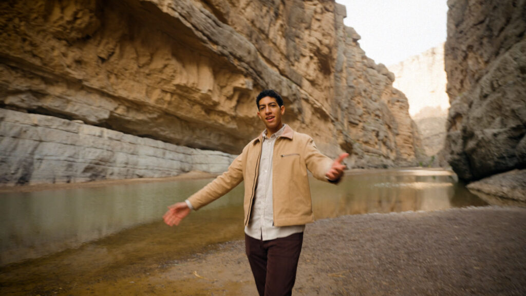 Male artist performing in canyon landscape with rocky cliffs and river